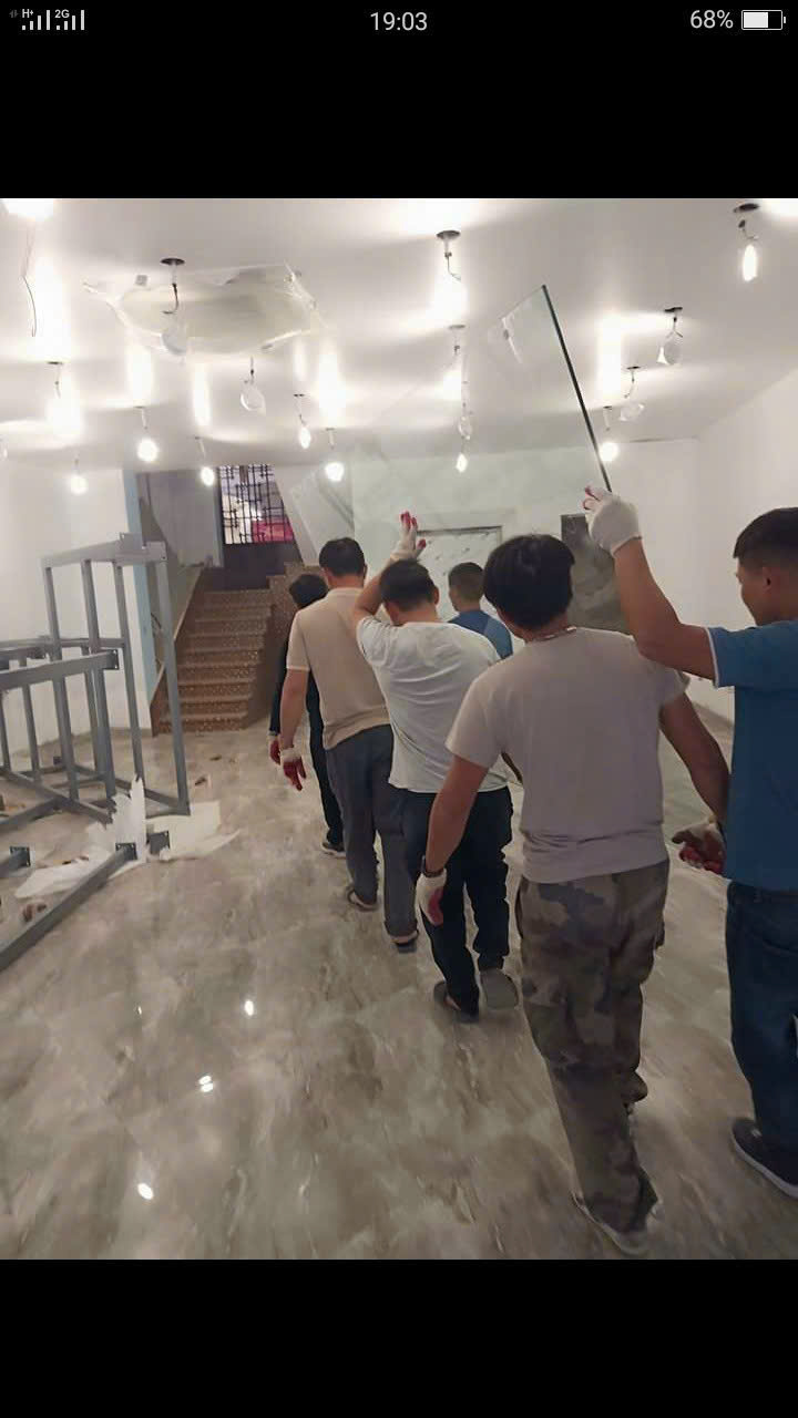 Nhân công phối hợp vận chuyển tấm kính lớn bên trong tòa nhà